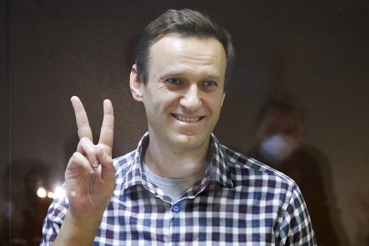 Alexei Navalny giving the peace sign and smiling.
