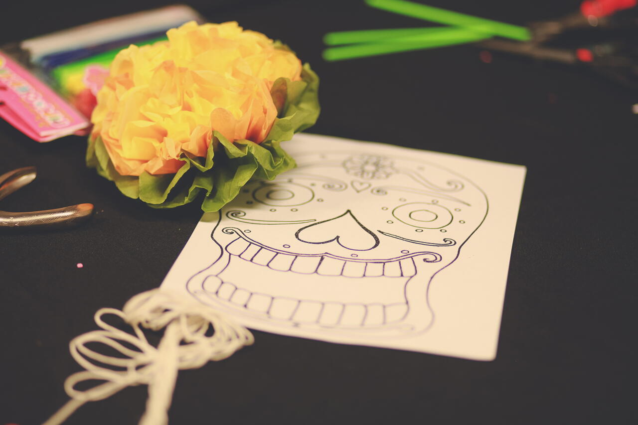 A calavera mask designed and a paper marigold.
