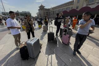 Viajeros con su equipaje esperan en una plaza de la estación de tren Beijing, en la capital de China, el viernes 29 de septiembre de 2023. (Foto AP/Andy Wong)