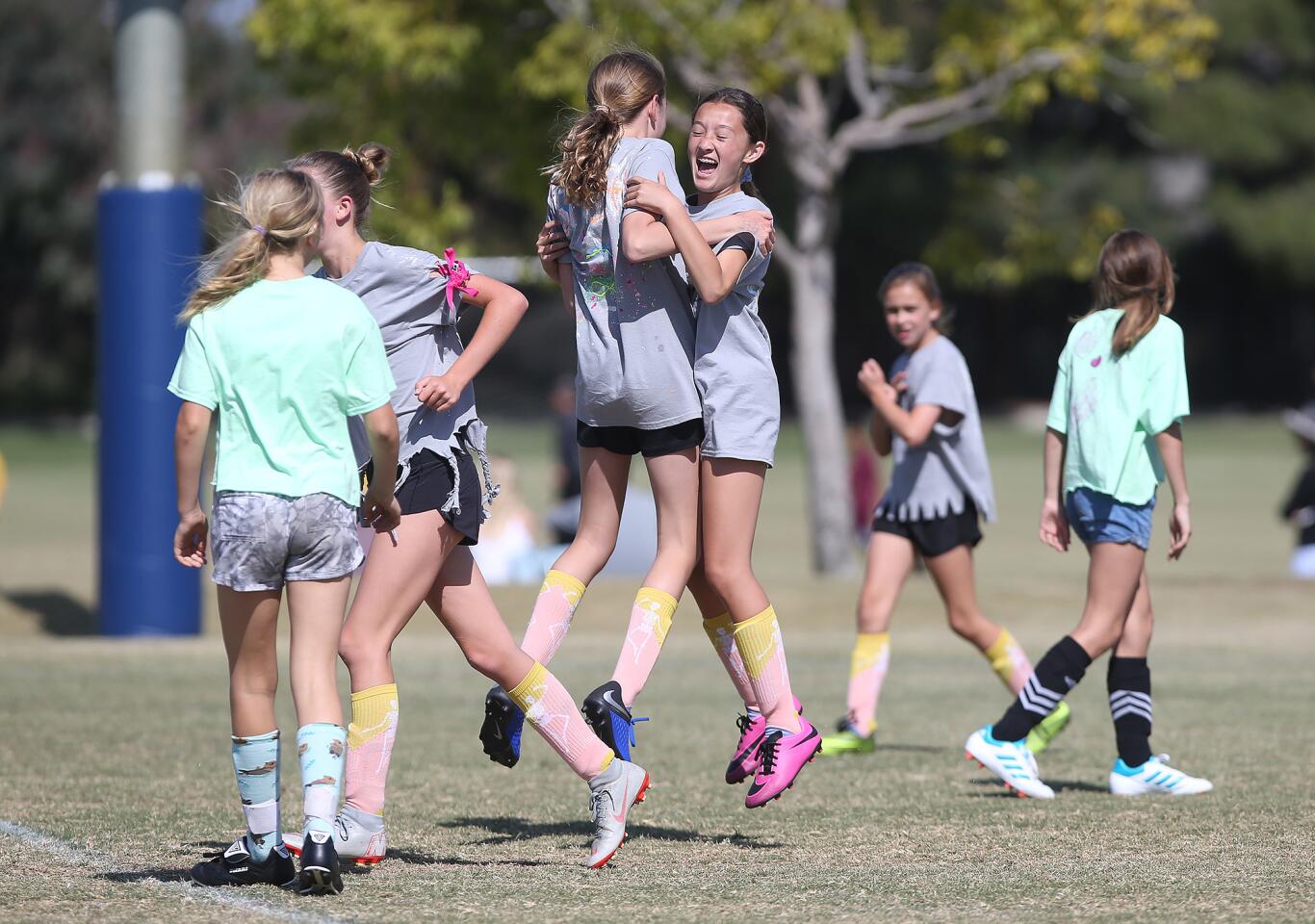 Our Lady Queen of Angels player Kyla Grant, in pink shoes, celebrates a goal with a teammate after she scored a goal against Newport Beach Eastbluff in the the girls’ fifth- and sixth-grade Silver Division pool-play match during the Daily Pilot Cup on Wednesday.
