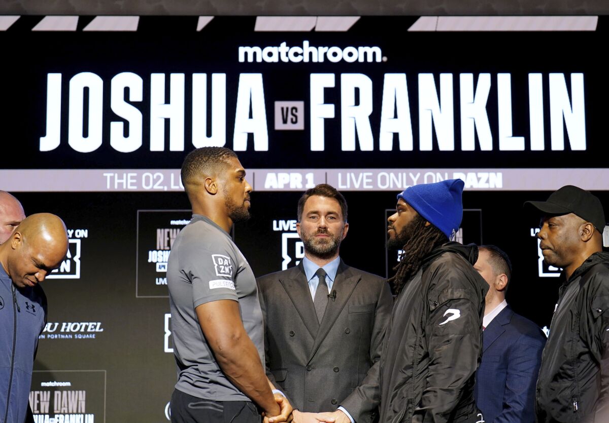 Boxing promoter Eddie Hearn stands in the centre as British boxer Anthony Joshua, centre left and US boxer Jermaine Franklin face off during a press conference, at the Nobu Hotel, in London, Wednesday March 29, 2023. The stakes are high for Anthony Joshua in a fight that comes at a crossroads in his career. The former two-time world champion takes on American boxer Jermaine Franklin at London’s O2 Arena on Saturday. (Zac Goodwin/PA via AP)