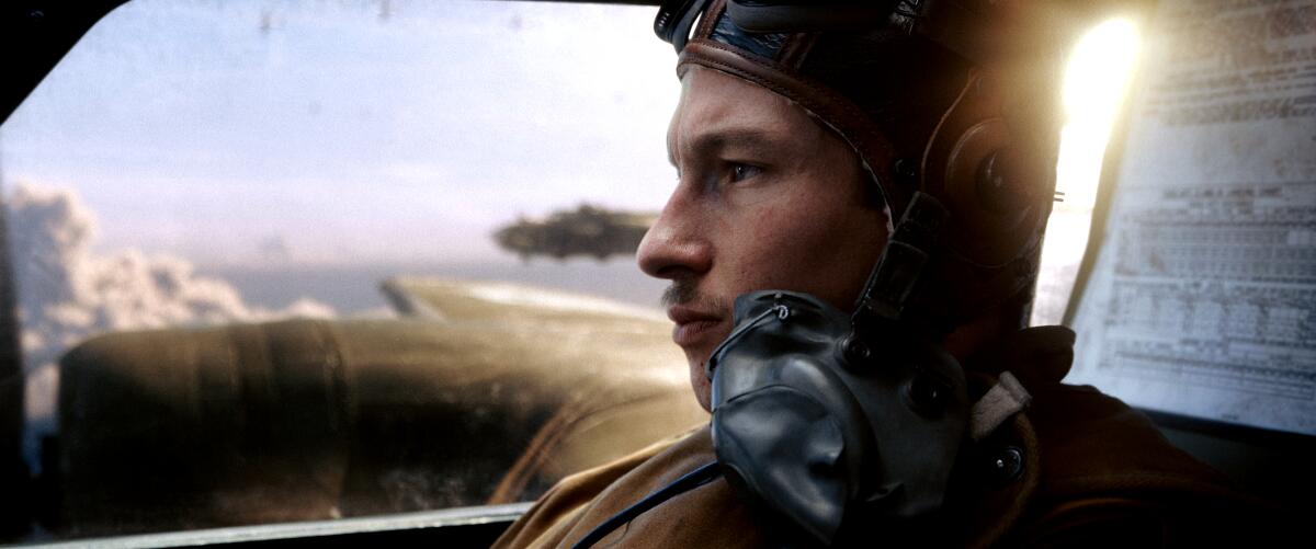 Callum Turner inside the cockpit of a WWII bomber with sky and clouds in the background.