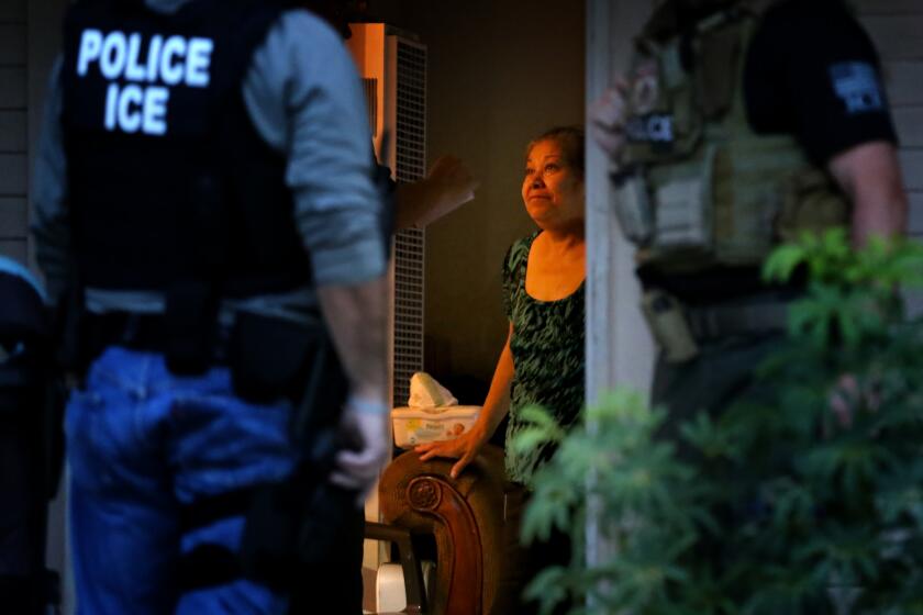 Immigration and Customs Enforcement officers looking for a fugitive migrant question his mother during a morning raid on his residence in Riverside on Aug. 12.