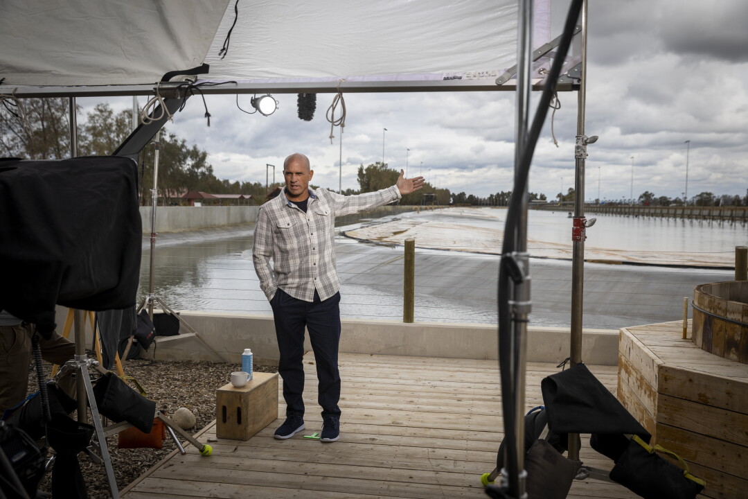 Kelly Slater lève le bras vers sa piscine à vagues pendant la production.