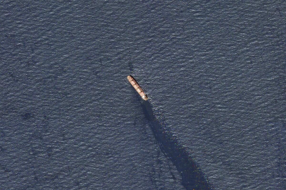 A cargo ship leaves a trail of oil in the water.