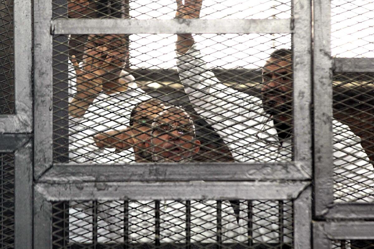 Muslim Brotherhood leader Mohammed Badie, bottom center, and organization member Salah Soltan, right, gesture during an appearance in a Cairo courtroom during the opening of their trial.