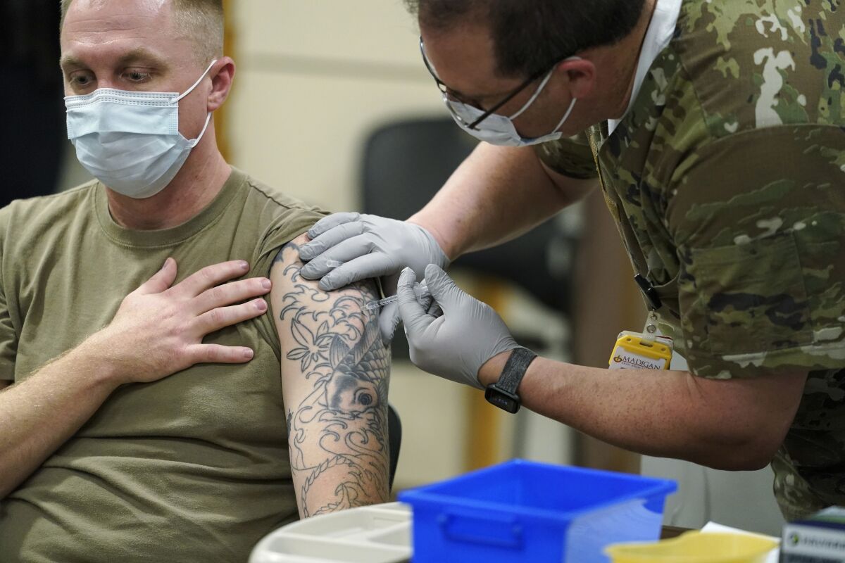 FILE - Staff Sgt. Travis Snyder, left, receives the first dose of the Pfizer COVID-19 vaccine given at Madigan Army Medical Center at Joint Base Lewis-McChord in Washington state, Dec. 16, 2020, south of Seattle. The Army says 98% of its active duty force had gotten at least one dose of the mandatory coronavirus vaccine as of this week’s deadline for the shots. (AP Photo/Ted S. Warren, File)