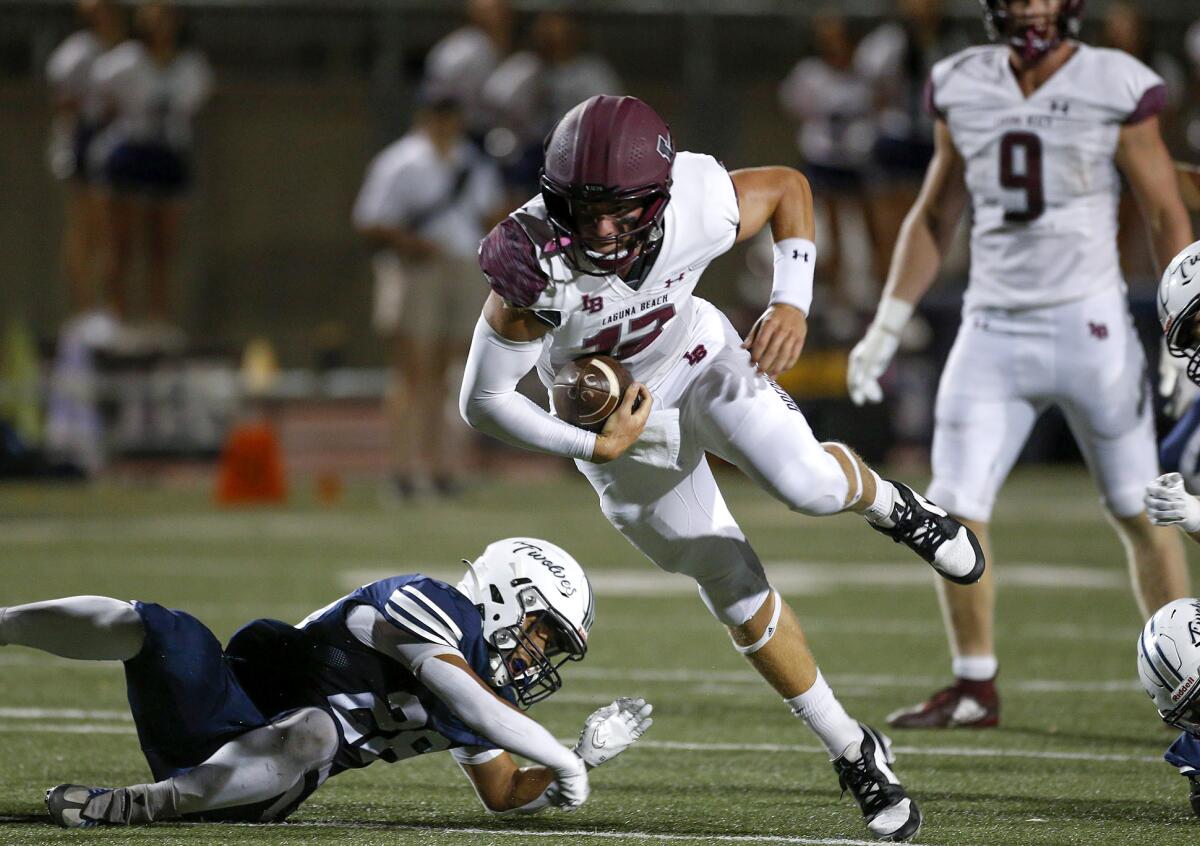 Laguna Beach quarterback Jackson Kollock (12) eludes a Northwood tackler as he runs for a touchdown on Friday.