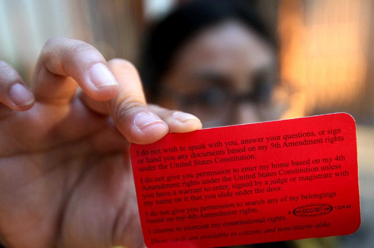 A DACA recipient who asked not to be identified holds up a red card that outlines constitutional rights.