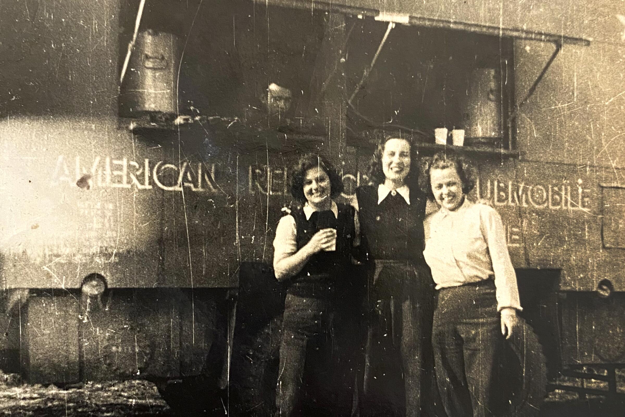 black and white photo of three women in front of a mobile Red Cross station 