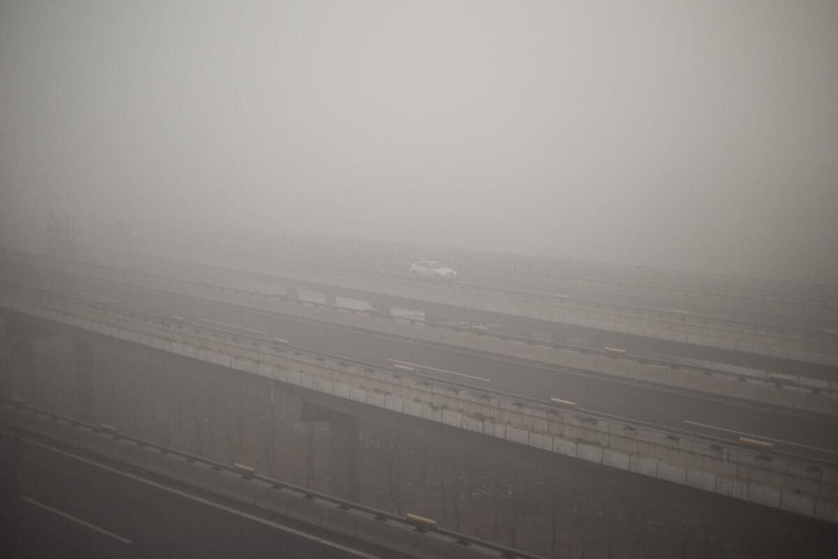 A car drives along a highway on a polluted day in Beijing on December 1, 2015. China has ordered thousands of factories to shut as it grapples with swathes of choking smog that were nearly 24 times safe levels on December 1, casting a shadow over the country's participation in Paris climate talks. A thick grey haze shrouded Beijing, with the concentration of PM 2.5, harmful microscopic particles that penetrate deep into the lungs, climbing as high as 598 micrograms per cubic metre AFP PHOTO / FRED DUFOURFRED DUFOUR/AFP/Getty Images ** OUTS - ELSENT, FPG, CM - OUTS * NM, PH, VA if sourced by CT, LA or MoD **
