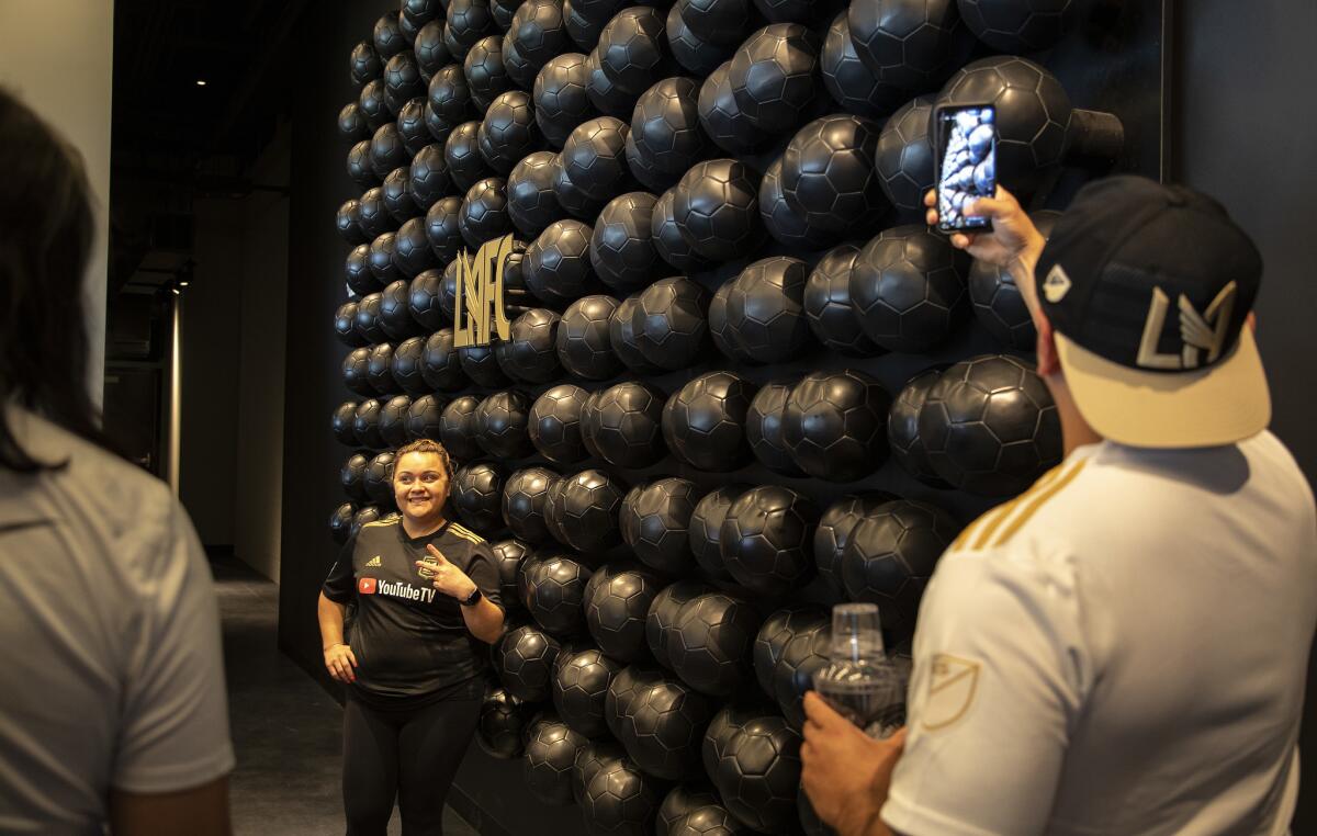 Fans take selfies against a wall of soccer balls at the Figueroa Club. (Gina Ferazzi / Los Angeles Times)