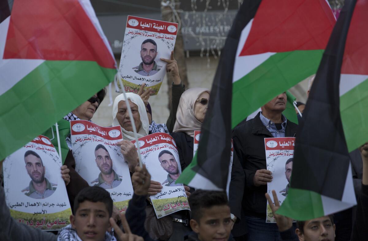 Protesters carry posters with pictures of Sami Abu Diak, a Palestinian prisoner in Israel who died Nov. 26, during a demonstration in the West Bank city of Ramallah.