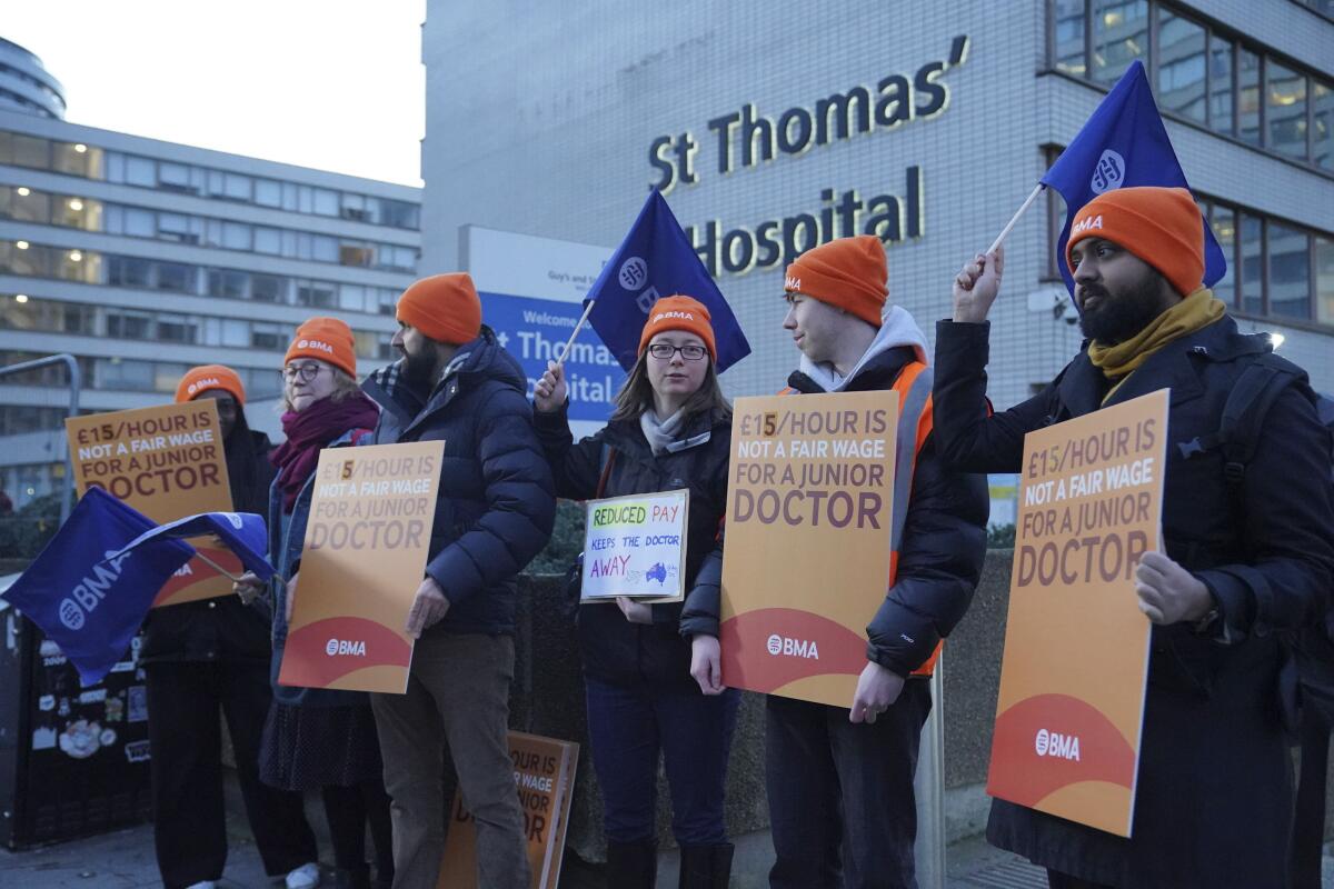 Striking doctors hold signs outside a hospital.