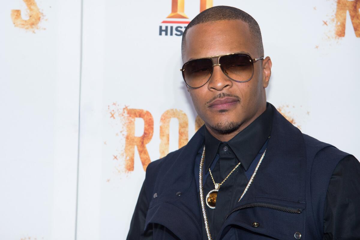 T.I. poses in sunglasses and a dark shirt and jacket