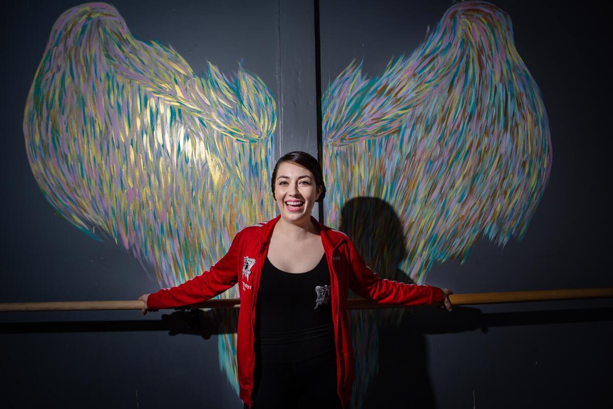 Ballet Folklórico founder Kareli Montoya poses for a portrait in front of rainbow chalk angel wings.