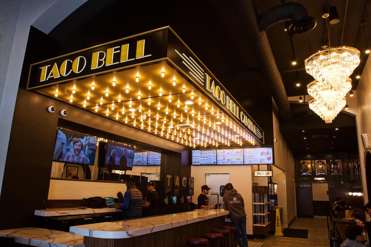 An interior of Taco Bell Cantina; to the left, over the bar, is a faux movie theater marquee, illuminated by rows of bulbs.
