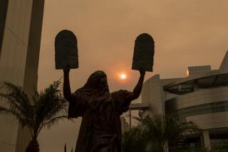 GARDEN GROVE, CA - SEPTEMBER 09: The sun and a bronze statue of Moses putting the ten commandments of two tables in the air are partially obscured with ash from Southland wildfires at the Christ Cathedral in Garden Grove Wednesday, Sept. 9, 2020. With so many fires burning, millions of people in the Bay Area, Central Valley and parts of Southern California are breathing dangerous levels of particle pollution. (Allen J. Schaben / Los Angeles Times)