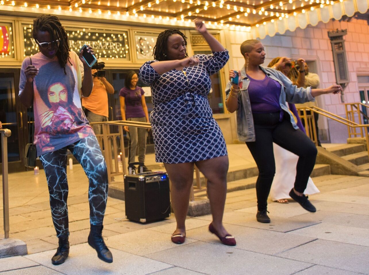 People dance during a candle light vigil in remembrance of Prince outside the Warner Theatre in Washington, DC.
