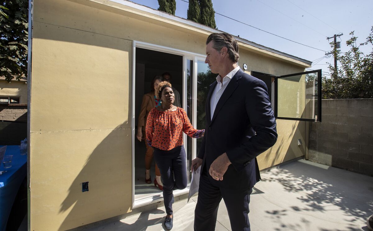 Gov. Gavin Newsom, right, chats with Felicia Smith, left, after a tour of her new garage conversion under construction in Los Angeles on Oct. 9. The governor signed several housing bills in Smith’s backyard.