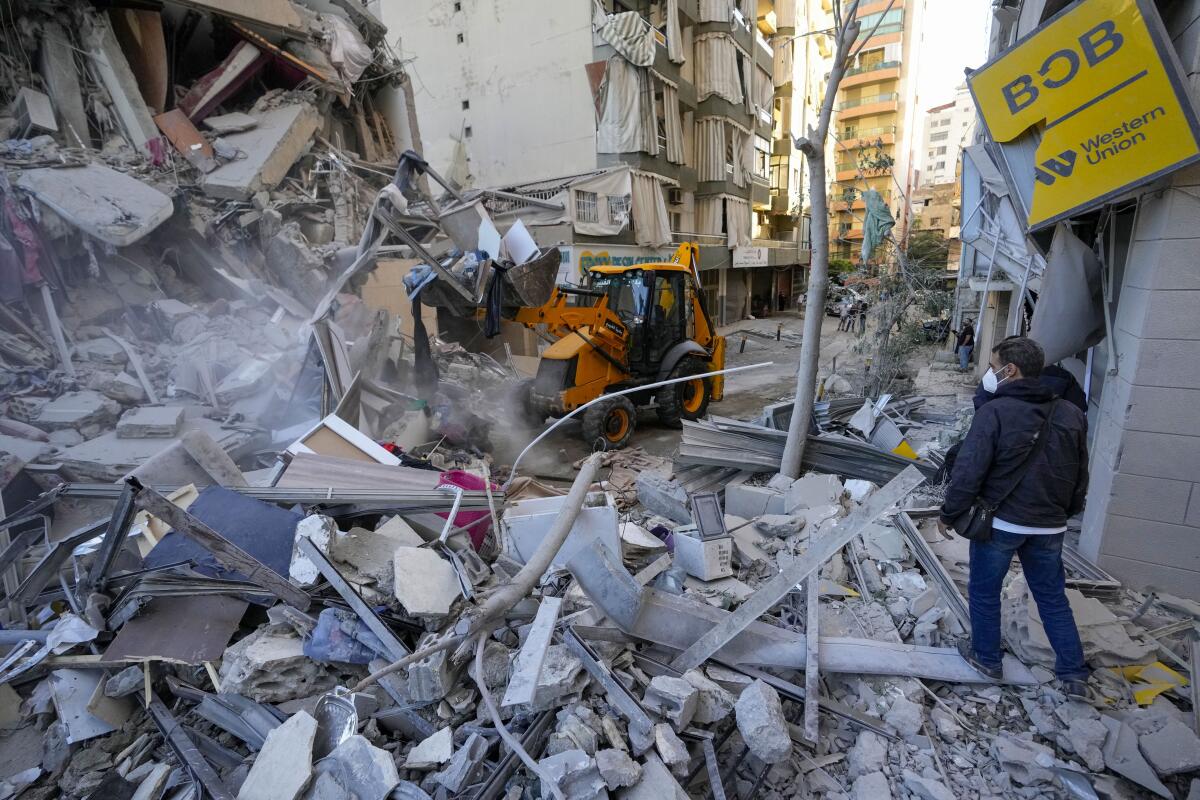 Rescue workers use a bulldozer to remove rubble of destroyed buildings at the site of an Israeli airstrike.