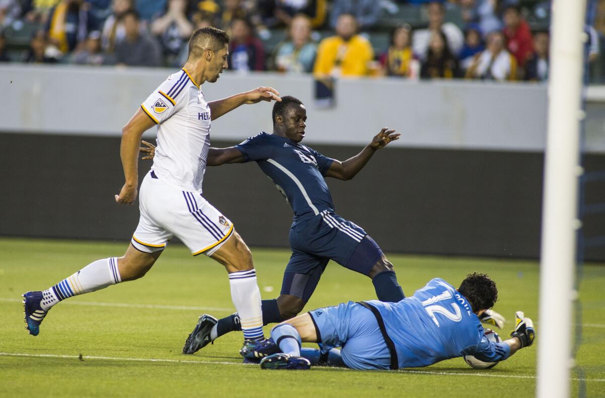 Galaxy goalkeeper Brian Rowe dives for the ball against Vancouver forward Kekuta Manneh on Saturday night at StubHub Center.