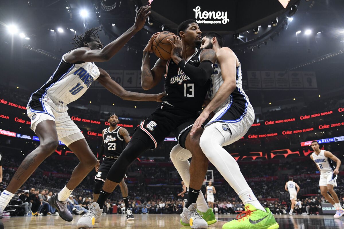Clippers forward Paul George, center, is double-teamed by Bol Bol, left, and Goga Bitadze of the Orlando Magic.
