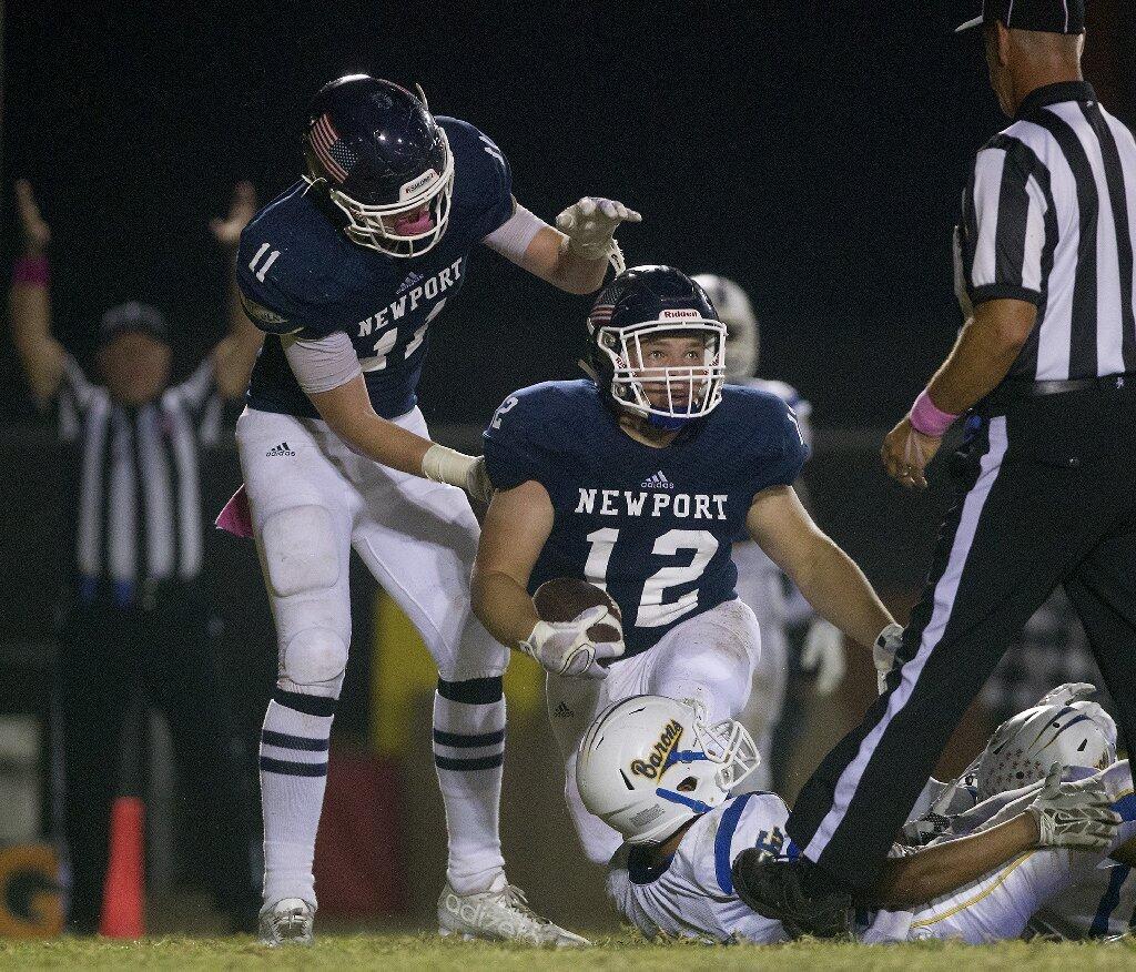 Newport Harbor High's Jamie McNeil (12) is congratulated by teammate Kobe Benter (11) on scoring a touchdown during the first half against Fountain Valley in a Sunset League season opener at Davidson Field on Thursday.