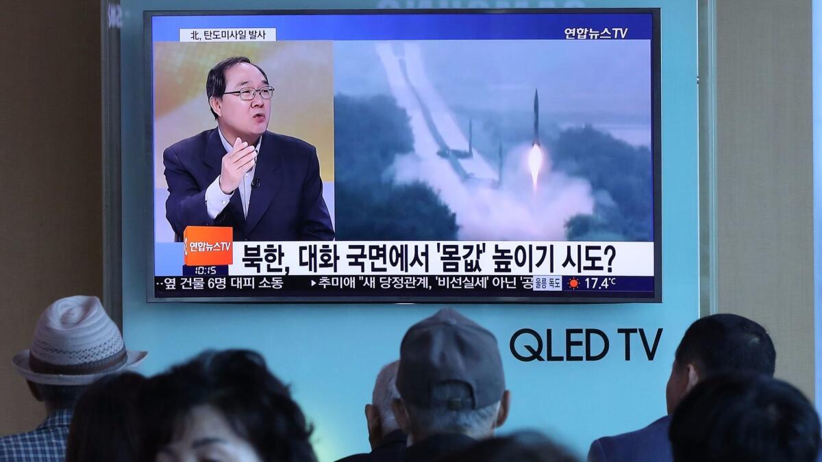 People at a railway station in Seoul watch a news program showing file footage of a North Korean missile launch.