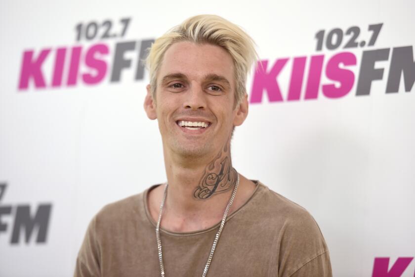 A man with blond hair and neck tattoo smiles 