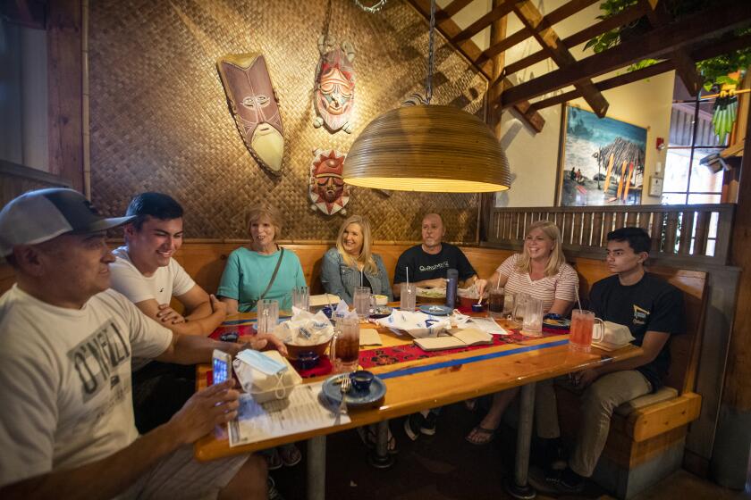 HUNTINGTON BEACH, CA - SEPTEMBER 08: Family celebrates birthdays with indoor dinner from left: Kirk Sumida, Justin Sumida, Ginny Winn, who is celebrating her 80th birthday, Sandi Lance, Shaun Lance, Suzanne Sumida and Devin Sumida, who is celebrating his 15th birthday, all of Huntington Beach, at Islands Restaurant in Huntington Beach Tuesday, Sept. 8, 2020. As COVID-19 risk dips, Orange County gets the OK from Gov. Newsom to reopen indoor dining at restaurants, movie theaters at 25% capacity. (Allen J. Schaben / Los Angeles Times)