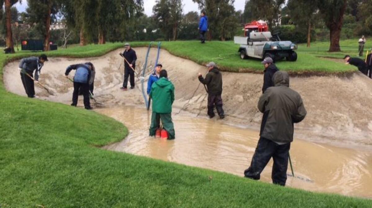 Grounds crew members work on a flooded bunker on Saturday before the resumption of the second round of the Genesis Open at the Riviera Country Club.