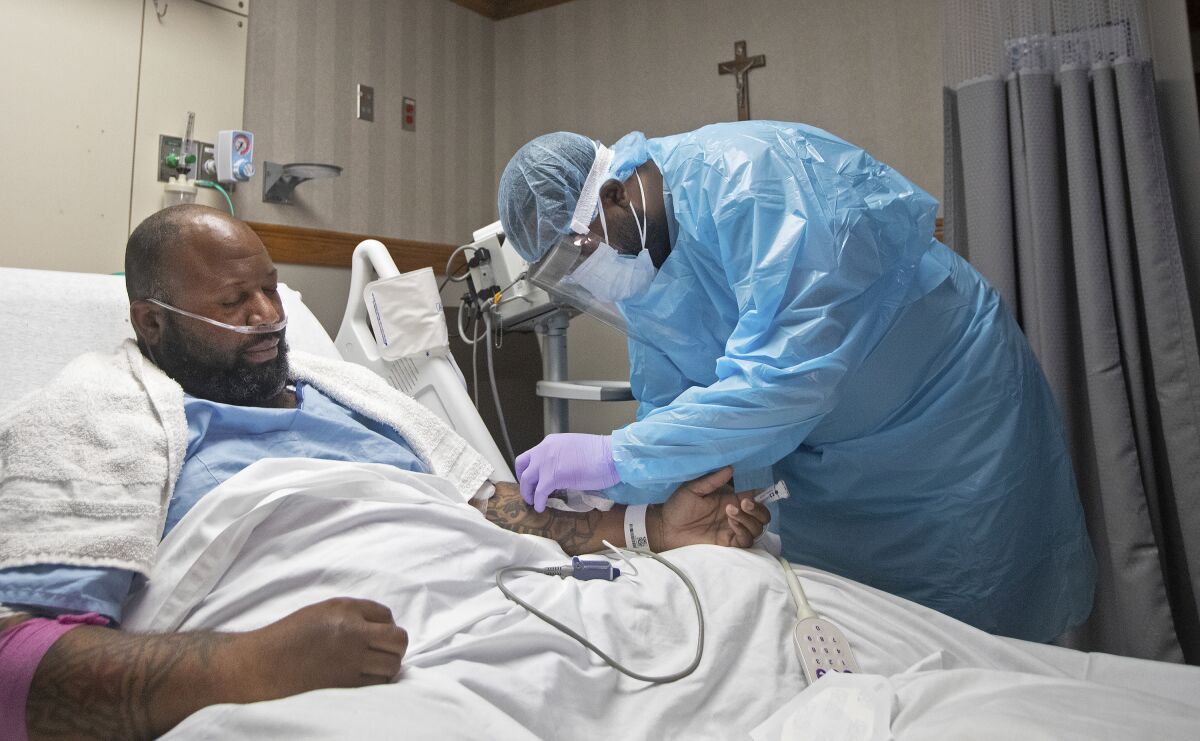 A nurse treats COVID-19 patient Cedric Daniels, 37, of Gonzales, La., at Our Lady of the Lake Regional Medical Center in Baton Rouge, Monday, Aug. 2, 2021. Louisiana is leading the nation in the number of new COVID cases per capita and remains one of the bottom five states in administering vaccinations. (AP Photo/Ted Jackson)