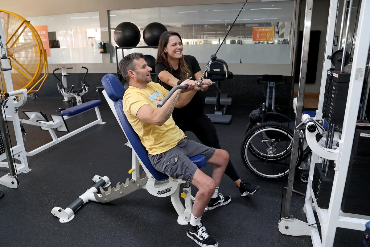 Personal trainer Ashley Griswold, top, helps start paraplegic Paul Ferguson off on his workout.