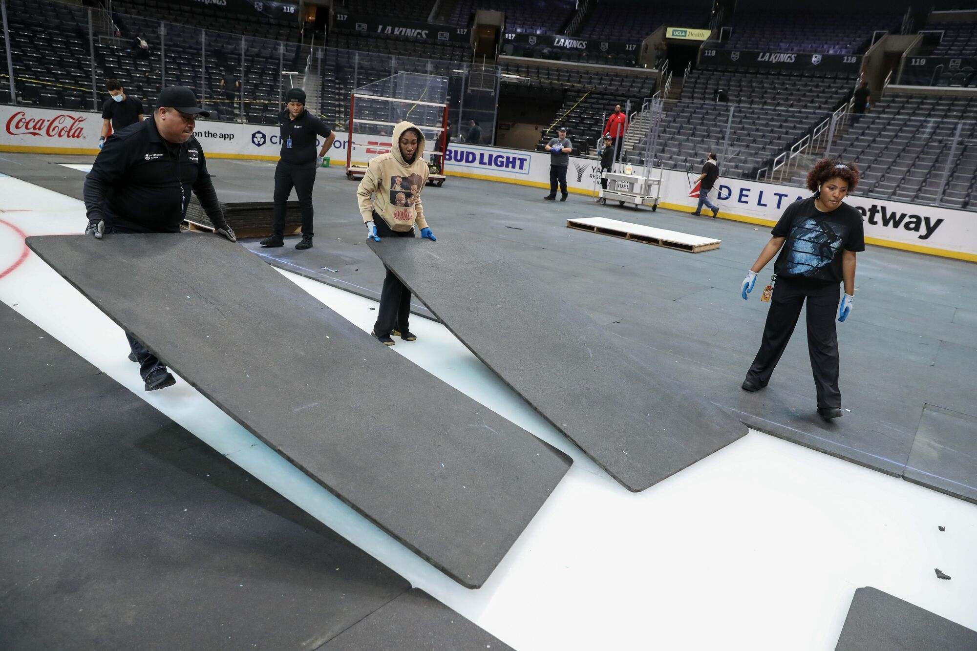 Employee at Crypto.com Arena remove rubber mats covering the ice.