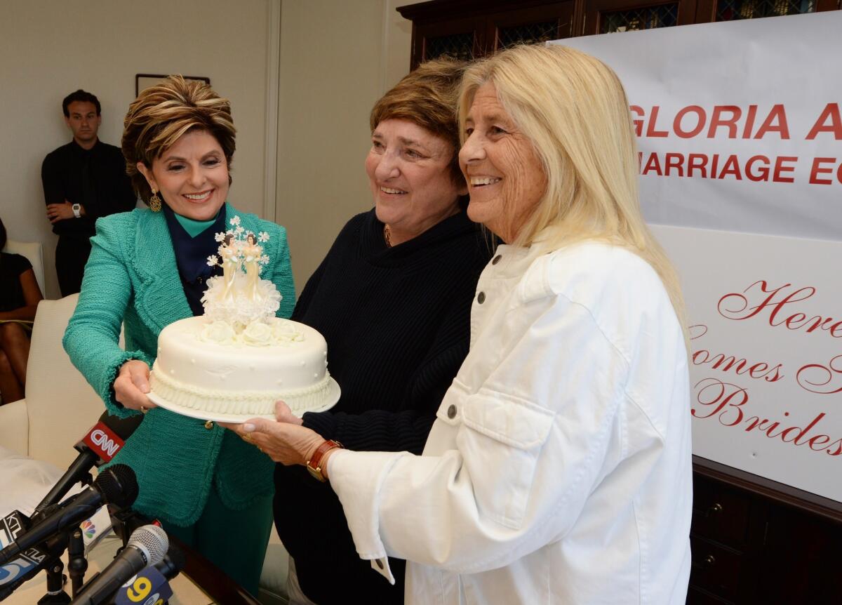 Attorney Gloria Allred, left, passes a wedding cake to Robin Tyler, center, and her wife, Diane Olson, at a news conference in Los Angeles, after the U.S. Supreme Court issued decisions on California's Proposition 8 and the federal Defense of Marriage Act.