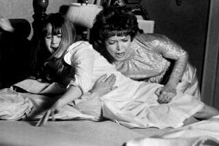 Ellen Burstyn tries to comfort Linda Blair on her shaking bed in a publicity photo from "The Exorcist."