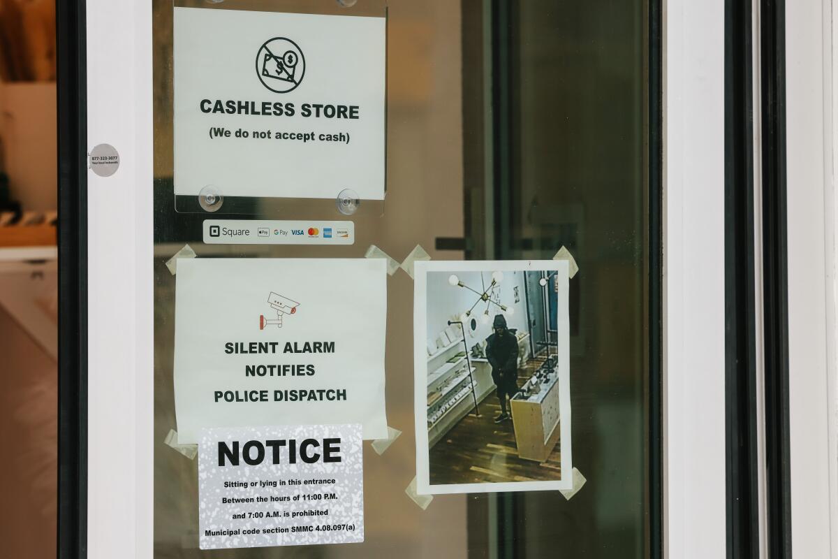 Signs in a store window warn "Silent alarm notifies police dispatch."