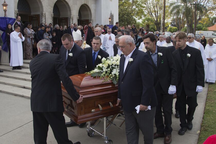 Pallbearers carry the casket of Damian Meins to an awaiting hearse after funeral services at St. Catherine of Alexandria.