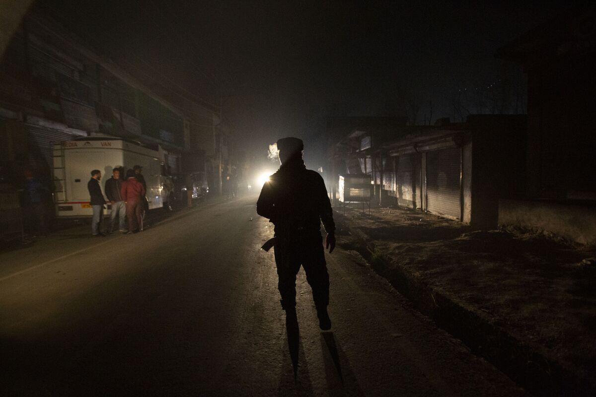 FILE - An Indian soldier guards near the site of an attack on the outskirts of Srinagar, Indian controlled Kashmir, on Dec. 13, 2021. A London-based law firm filed an application with British police Tuesday seeking the arrest of India's army chief and a senior Indian government official over their alleged roles in war crimes in disputed Kashmir. Law firm Stoke White said it submitted extensive evidence to the Metropolitan Police’s War Crimes Unit documenting how Indian forces headed by Gen. Manoj Mukund Naravane and Home Affairs Minister Amit Shah were responsible for the torture, kidnapping and killing of activists, journalists and civilians. (AP Photo/Mukhtar Khan, File)