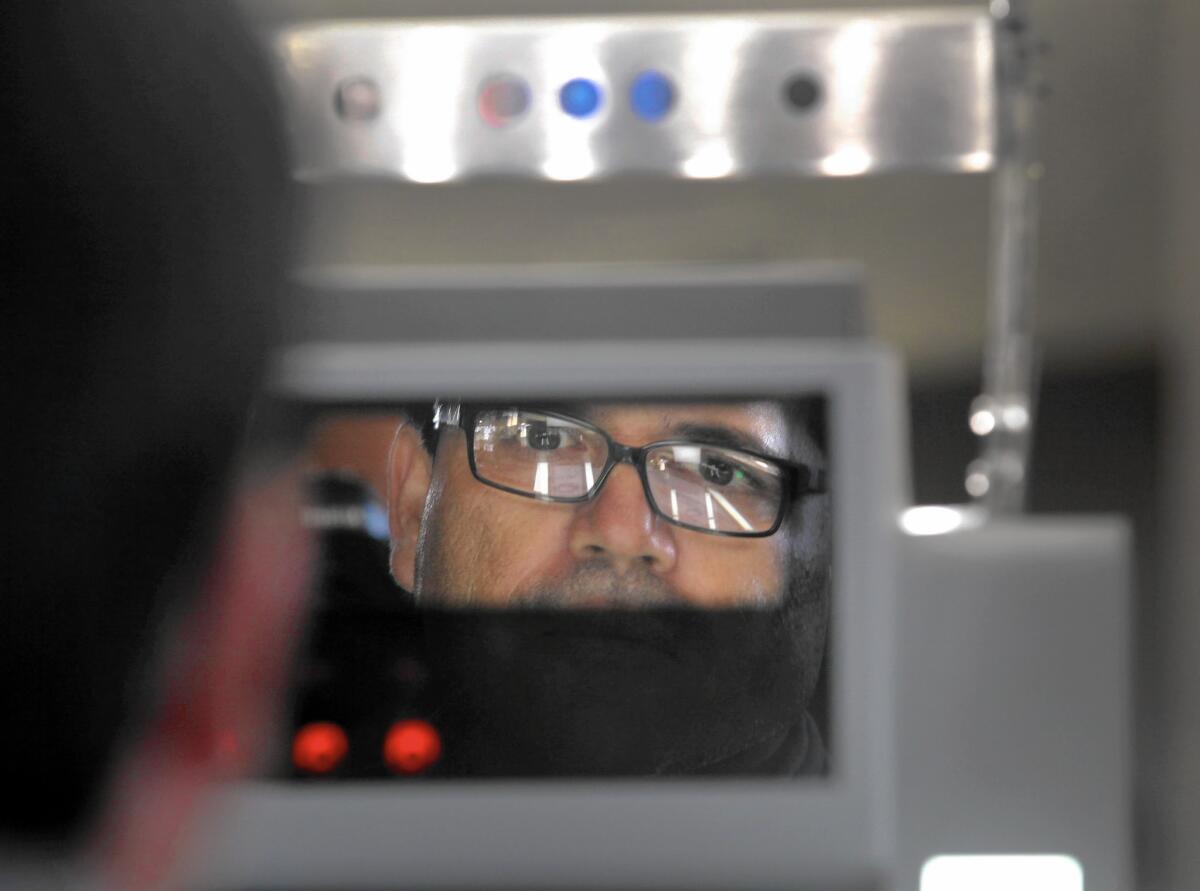 A man stands before a biometric machine being tested at the Otay Mesa port of entry. The system scans the face and irises and records the information, which will be used to track non-U.S. citizens who travel across the border.