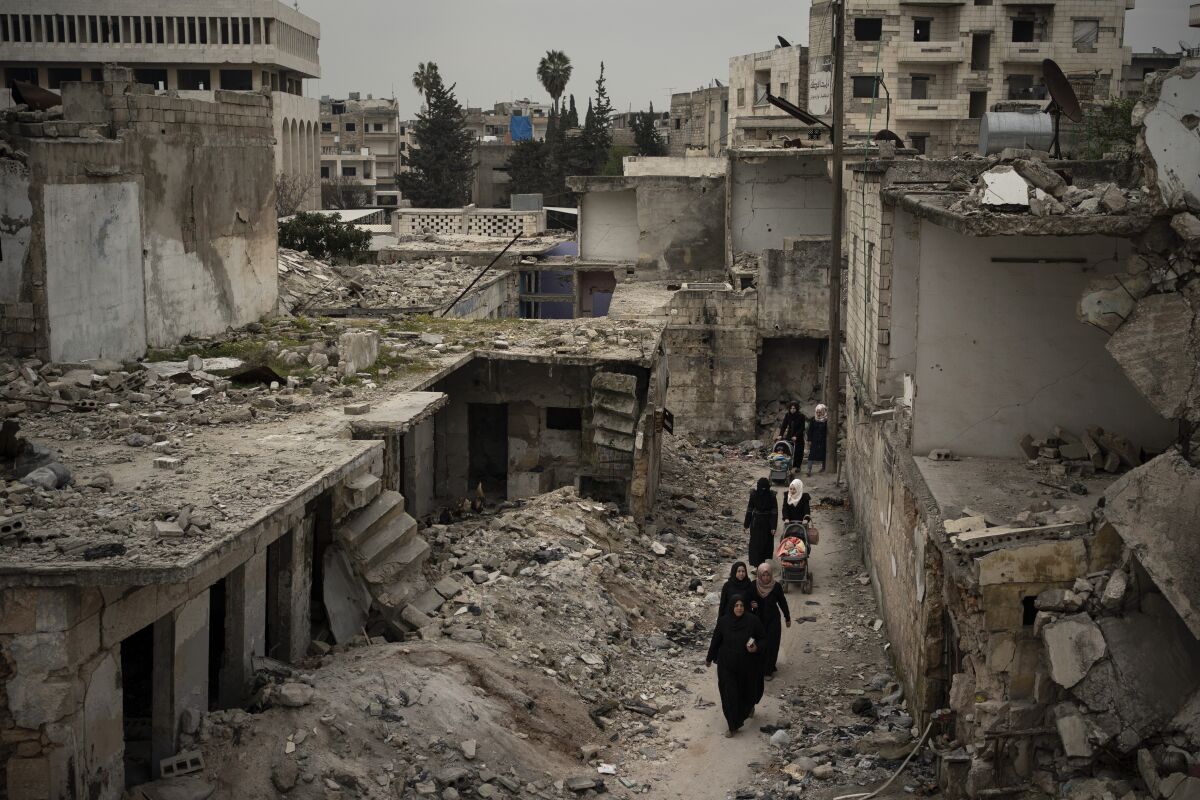 FILE - Women walk in a neighborhood heavily damaged by airstrikes in Idlib, Syria, March 12, 2020. Syrians in the last major rebel stronghold in the war-ton country are living in fear of the effects of Russia closing down the only border crossing into the northwestern province of Idlib. Aid agencies warn that if Russia vetoes the resolution that would maintain two border crossing points from Turkey to deliver humanitarian aid, food would be depleted in Idlib and surrounding areas by September, 2022, putting the lives of some 4.1 million people, at risk. (AP Photo/Felipe Dana, File)