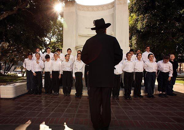 Rabbi Leibel Cohen, choir director of Cheder Menachem Elementary School, leads students as they practice before a Hanukkah celebration at Los Angeles City Hall.