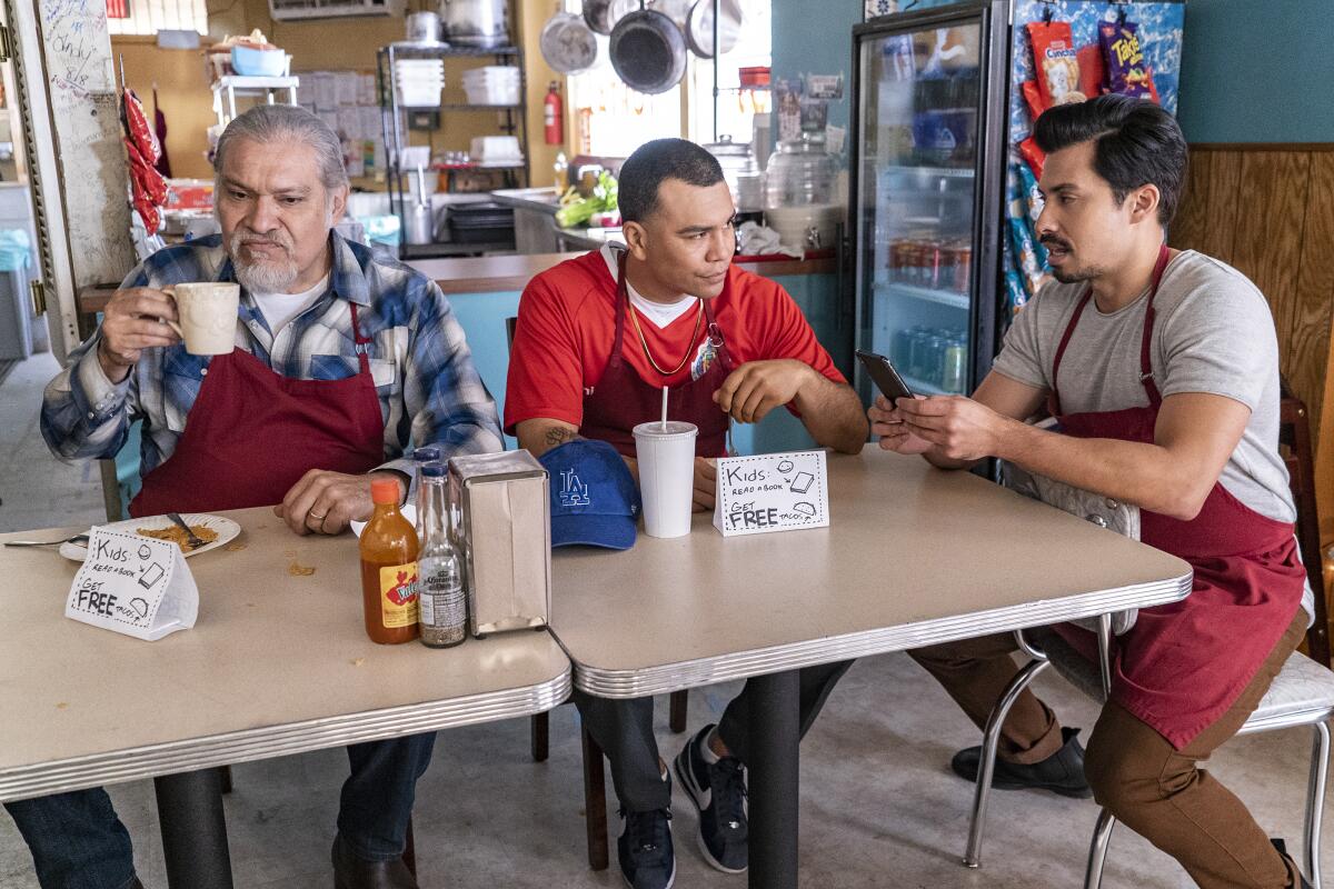 Joseph Julian Soria, Joaquin Cosio and Carlos Santos sit at a table in Netflix's "Gentified."