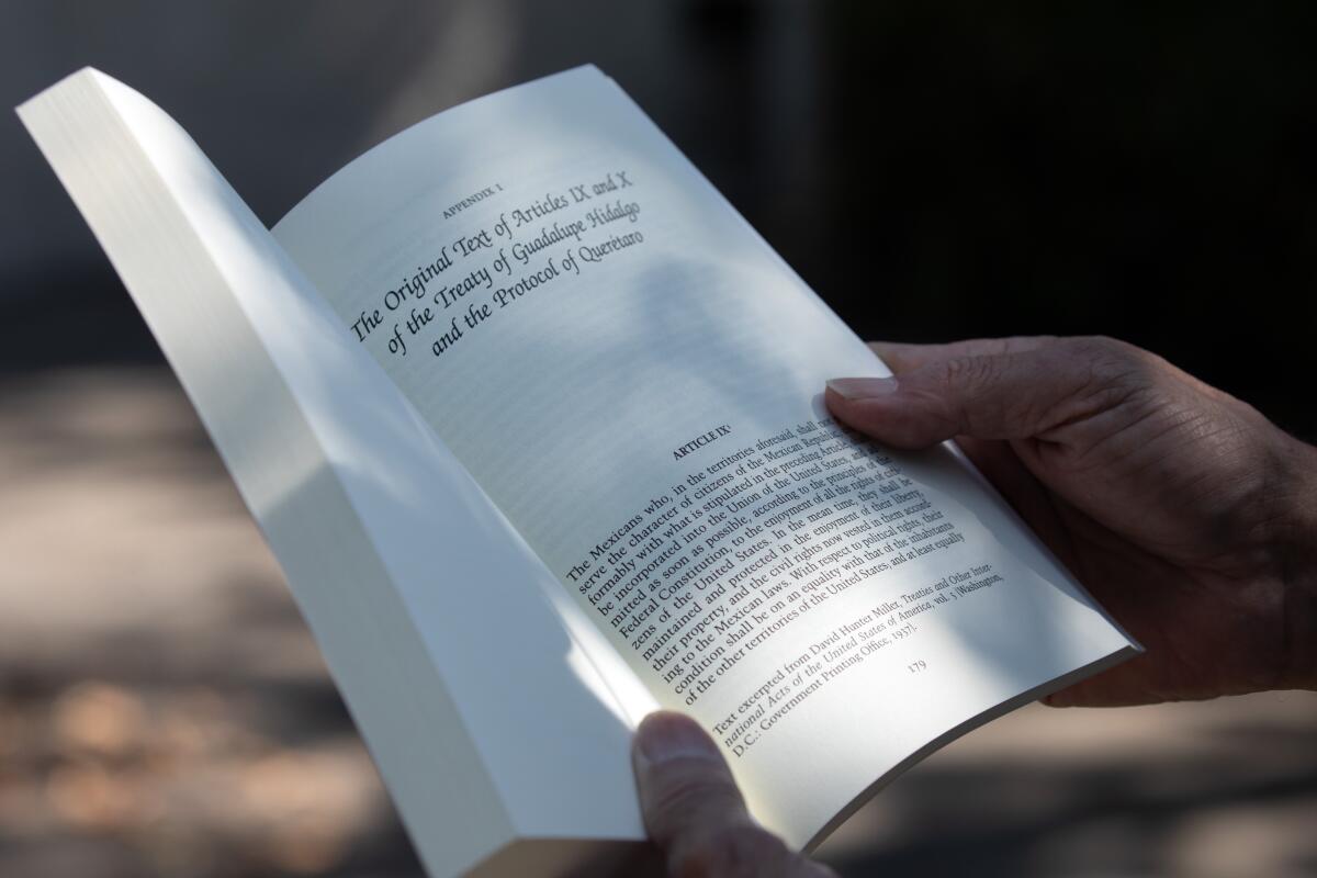 A close-up frame of hands holding an open soft-cover book.