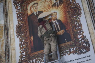 A Syrian opposition fighter tears a painting of two men
