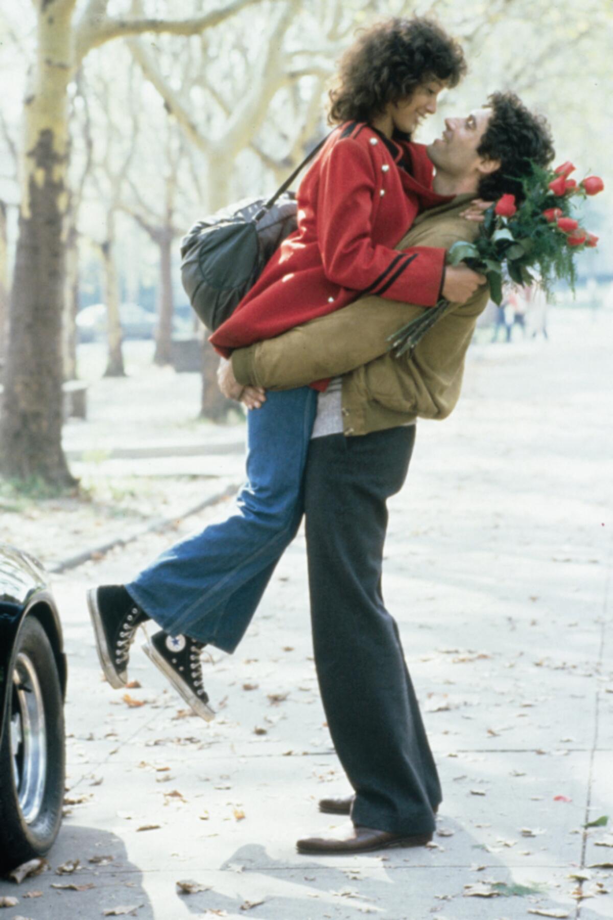 A man lifts a woman holding flowers