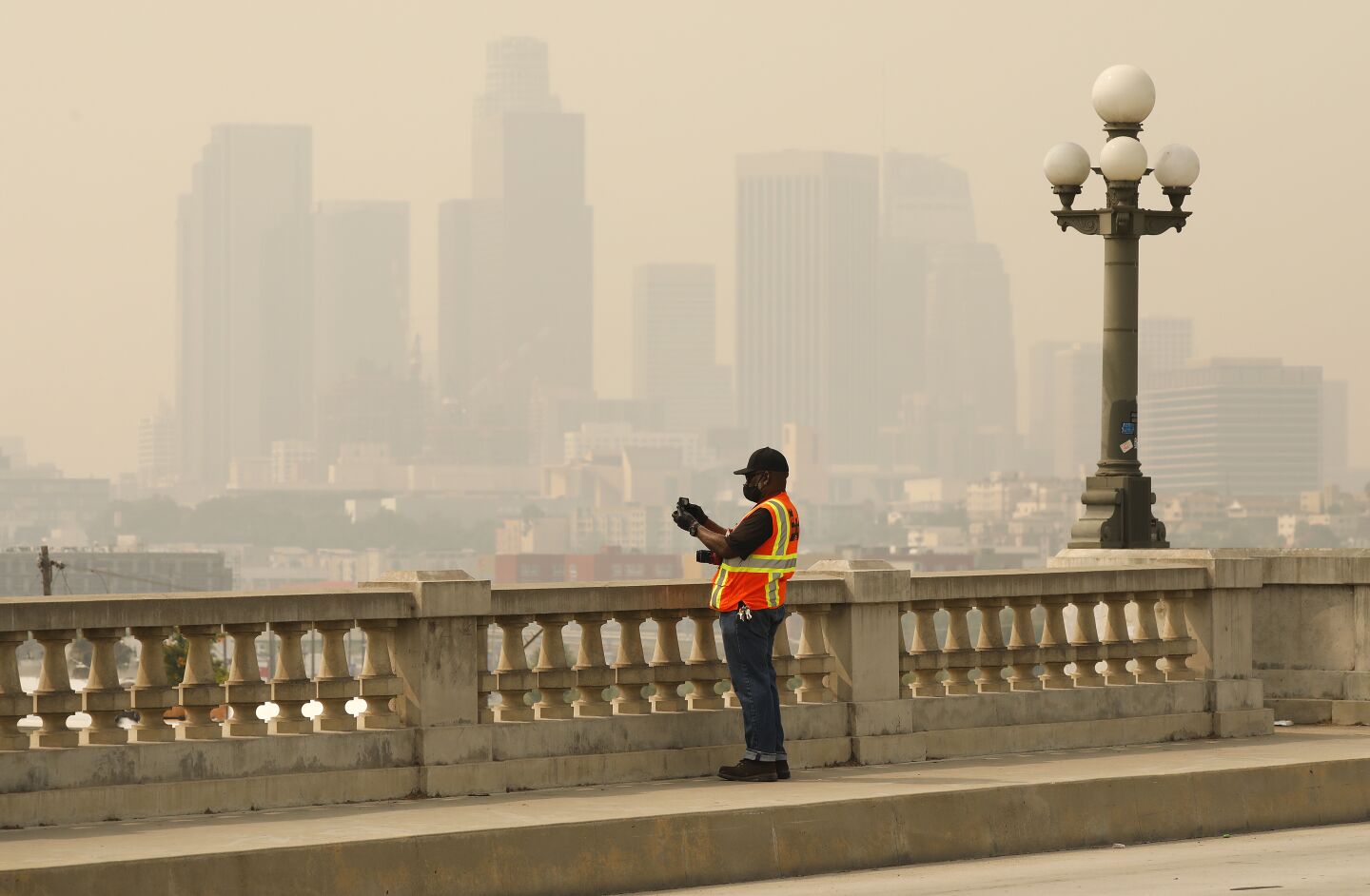 Brooks Hubbard with the U.S. Army Corps of Engineers takes photos from the historic North Broadway Bridge over the Los Angeles River Tuesday morning as smoke and ash from the Bobcat fire cloak the area.