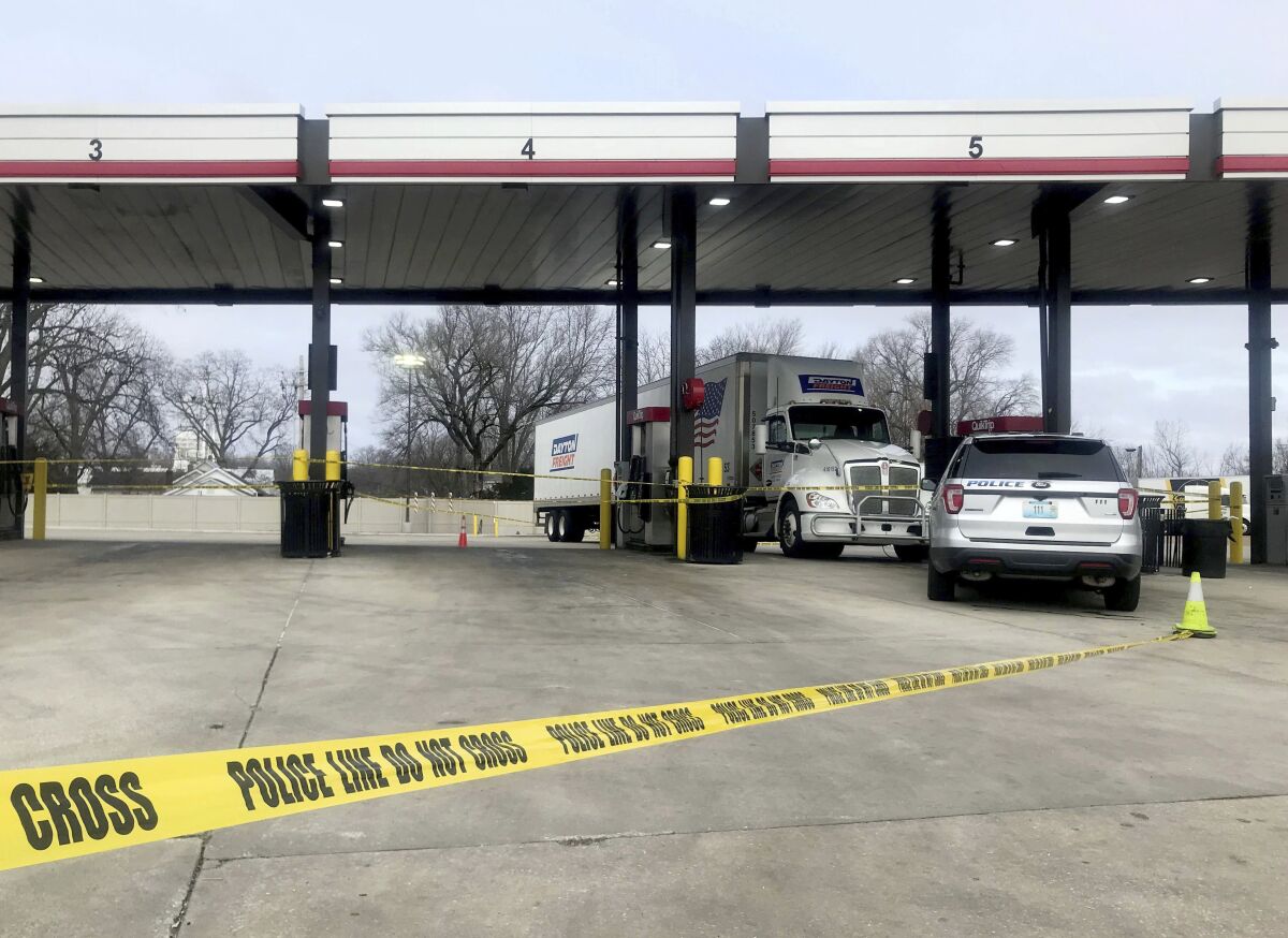 A tractor trailer is stopped behind police tape as law enforcement investigate the scene of a carjacking and shooting at a QuikTrip in St. Peters, Mo., on Wednesday, Dec. 29, 2021. Officials believe the suspect was the same person who fatally shot a sheriff's deputy in Wayne County, Ill., earlier Wednesday, a St. Peters police spokesperson said. (Hillary Levin/St. Louis Post-Dispatch via AP)