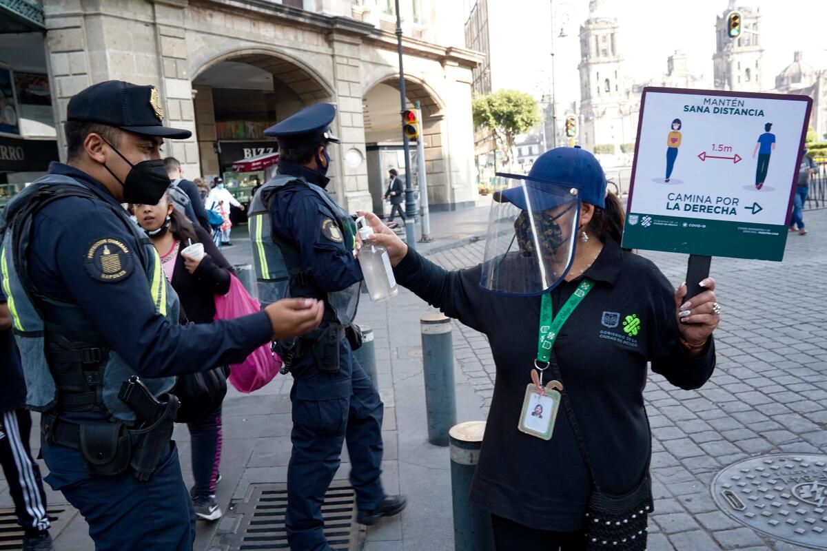 Rocio Ortega holds a sign urging people to maintain a safe distance as she distributes gel in downtown Mexico City.